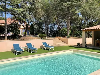 a swimming pool with two blue chairs next to at Villa Bois Romay dans le Luberon avec piscine, tennis et pétanque. in La Bastide-des-Jourdans