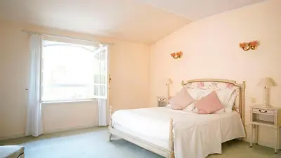a bedroom with a white bed with pink pillows at Villa Bois Romay dans le Luberon avec piscine, tennis et pétanque. in La Bastide-des-Jourdans
