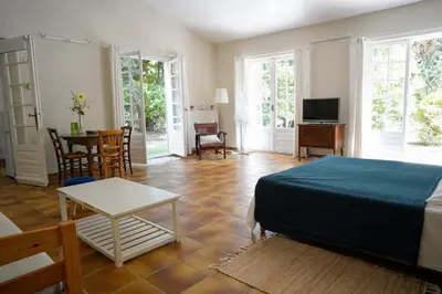 a bedroom with a bed and a living room with a table at Villa Bois Romay dans le Luberon avec piscine, tennis et pétanque. in La Bastide-des-Jourdans