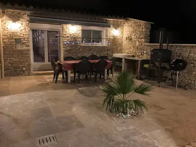 a patio with a table and chairs and a brick wall at Au milieu des Piboules de Provence. in LʼIsle-sur-la-Sorgue