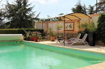 a swimming pool with two chairs and a gazebo at Les Moineaux in Rustrel