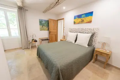 a white bedroom with a bed and a mirror at La Bastide des Lavandins in Le Thor