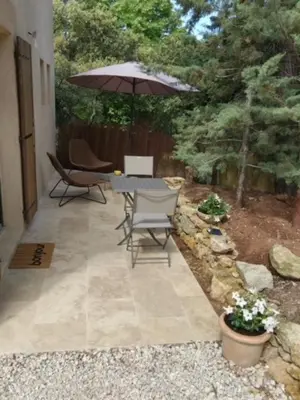 a patio with a table and chairs and an umbrella at Maison dans la pinède in Rognes