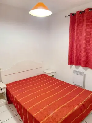 a bedroom with a red bed with a red curtain at Maison confortable Saint-Saturnin in Saint-Saturnin-lès-Avignon