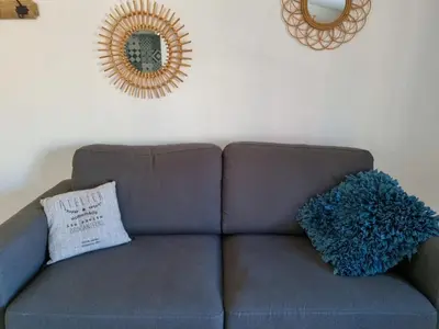 a couch with a pillow and a mirror on the wall at Un balcon sur les toits d'Aix in Aix-en-Provence