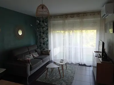 a living room with a couch and a window at LE SOLEIL DU LUBERON - T2 avec Terrasse, Parking et Clim in LʼIsle-sur-la-Sorgue