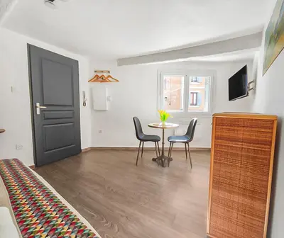 a room with a table and chairs and a black door at Les Amandiers - L'Isle d'Or in LʼIsle-sur-la-Sorgue