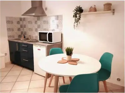 a kitchen with a white table and green chairs at Appartement indépendant, Hyper-centre pittoresque in Salon-de-Provence