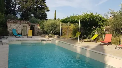 a swimming pool with colorful chairs sitting around it at le moulin in Crillon-le-Brave