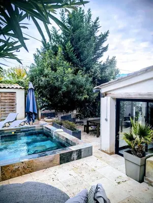 a swimming pool in a backyard with a table and an umbrella at Maison avec piscine, jacuzzi et sauna privatifs - Mas de Nebbas in Aix-en-Provence