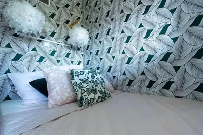 a bed with two pillows and a wall with leaves at Studio cosy à proximité du centre ville in Aix-en-Provence