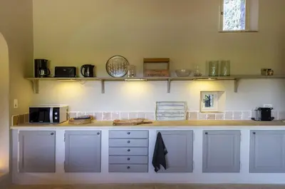 a kitchen with white cabinets and shelves on the wall at Mas De Rosemarie in Joucas