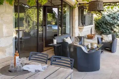 a patio with a table and chairs and a glass door at Mas De Rosemarie in Joucas