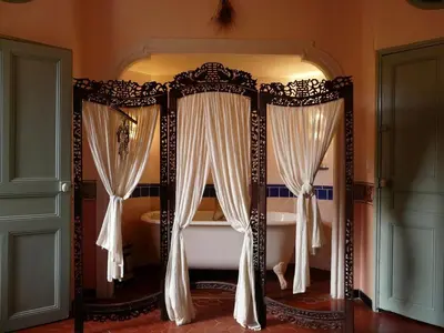a bedroom with a canopy bed with white curtains at Lou Amourie in Roussillon