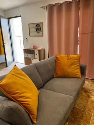 a couch with two yellow pillows in a living room at Magnifique maisonnette Dépendance avec Piscine in Châteaurenard