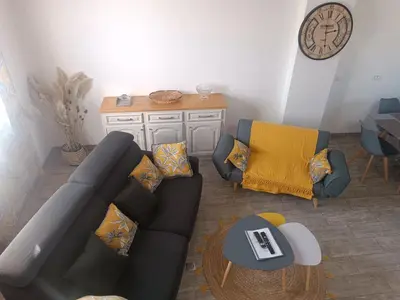 a living room with a couch and chairs and a clock at La Remise de Guytou et Spa in Cheval-Blanc
