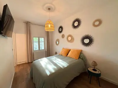 a bedroom with a bed and mirrors on the wall at Appartement eygalieres avec petit jardin in Eygalières