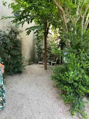 a garden with two chairs and a tree and bushes at Appartement eygalieres avec petit jardin in Eygalières