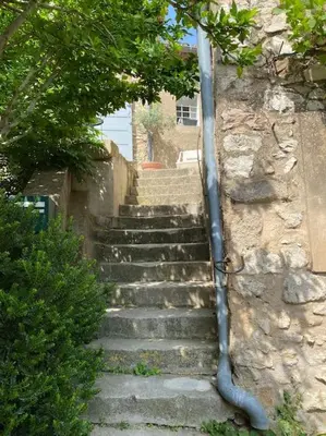 a set of stone stairs with a pipe on a wall at Appartement eygalieres avec petit jardin in Eygalières