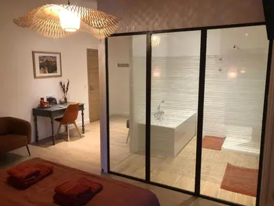 a bedroom with a tub and a dining room with a table at Le Mas Justin in Gordes