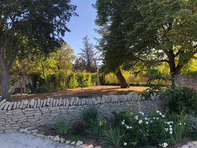 a garden with a stone wall and trees and flowers at Le Mas Justin in Gordes