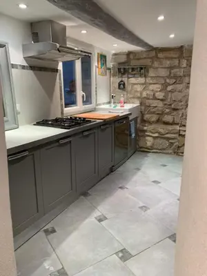 a kitchen with gray cabinets and a stone wall at La Maison Rose in Caromb