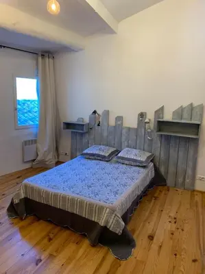 a bedroom with a bed in a room with wooden floors at La Maison Rose in Caromb