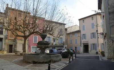 a statue in the middle of a street with buildings at La Maison Rose in Caromb