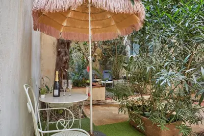 a table and chair under an umbrella in a garden at Appart Aix sauna jacuzzi balneo spa privatifs hyper centre historique cour intérieur in Aix-en-Provence