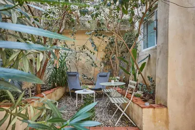 a patio with two chairs and a table in a garden at Appart Aix sauna jacuzzi balneo spa privatifs hyper centre historique cour intérieur in Aix-en-Provence