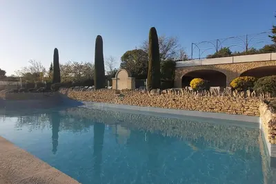 a swimming pool in front of a stone wall at Bastidon Plein Sud in Gordes