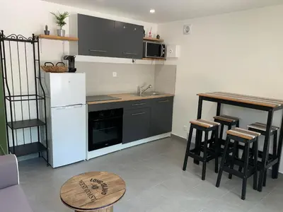 a kitchen with a white refrigerator and a table at Charmant logement avec un extérieur et un jacuzzi in Lançon-Provence