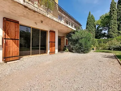 a house with large glass doors and a gravel driveway at Gites Partage des Eaux L'isle sur la Sorgue in LʼIsle-sur-la-Sorgue