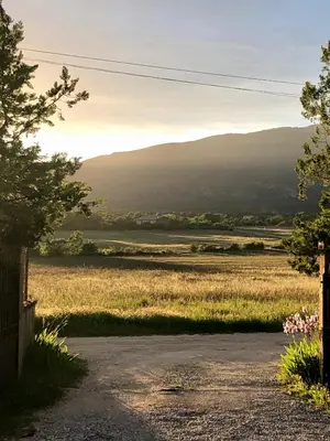a road leading to a field with mountains in the distance at Paisible gîte moderne avec vue sur le Luberon in La Motte-dʼAigues
