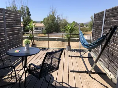 a patio with a table and a hammock on a deck at Ma place au sud terrasse à 2 pas d’Aix in Éguilles