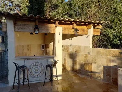 a patio with two bar stools and a wall at Gîte de Fanny du Moulin de Tartay en Avignon in Avignon