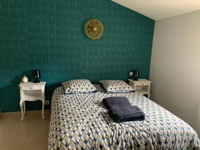 a bedroom with a bed and a green wall at Au cœur de l’Isle sur sorgue in LʼIsle-sur-la-Sorgue