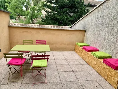 a patio with a table and chairs and a wall at Au cœur de l’Isle sur sorgue in LʼIsle-sur-la-Sorgue