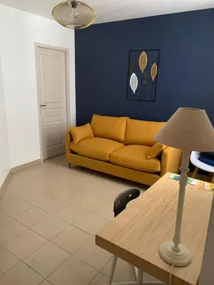 a living room with a yellow couch and a table at Au cœur de l’Isle sur sorgue in LʼIsle-sur-la-Sorgue
