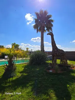 a statue of a giraffe standing next to a palm tree at L'endroit incontournable in Les Baïsses