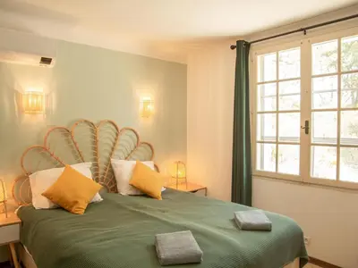 a bedroom with a green bed with a large window at Villa Cantirane in Saint-Pierre-de-Vassols