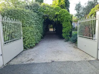 an entrance to a garden with two white gates at Chambres d'Hôtes dans villa avec piscine chez Raphaële in LʼIsle-sur-la-Sorgue