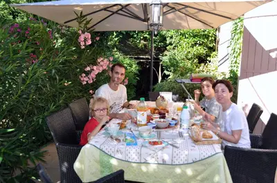 a group of people sitting at a table eating food at Chambres d'Hôtes dans villa avec piscine chez Raphaële in LʼIsle-sur-la-Sorgue