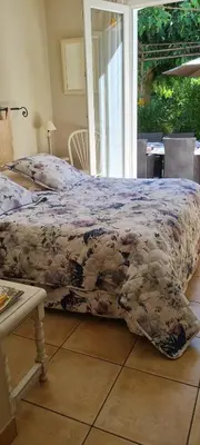 a bed with a blanket on it in a bedroom at Chambres d'Hôtes dans villa avec piscine chez Raphaële in LʼIsle-sur-la-Sorgue