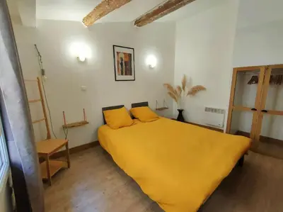 a bedroom with a large yellow bed with yellow sheets at Maison de ville au coeur du centre historique, parking gratuit in Apt