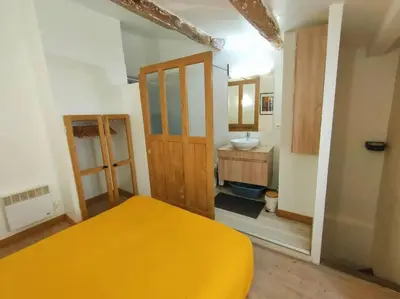 a bedroom with a yellow bed and a sink at Maison de ville au coeur du centre historique, parking gratuit in Apt