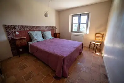 a bedroom with a bed with a purple blanket and a window at Domaine Les Perpetus in La Tour-dʼAigues