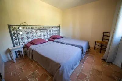a room with two beds and a chair at Domaine Les Perpetus in La Tour-dʼAigues