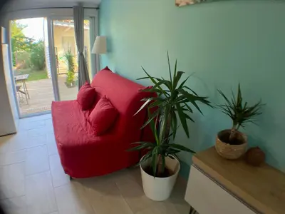 a red couch in a living room with two plants at Anse Coco Luberon - Au calme, gite en Provence avec piscine partagée et parking in Pertuis