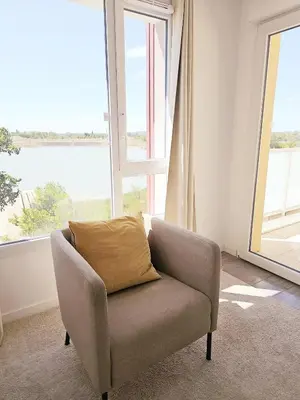 a chair in a room with a large window at Lakeside Provence - Appartement classé 4 étoiles, Vue sur le lac de Monteux, Parking sous-sol, double clim in Monteux